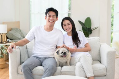 Neşeli bir çift kanepede birlikte oturur, güneşli bir yerde tatlı köpekleri ile atıştırmalıkları paylaşır..