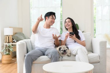 Neşeli bir çift kanepede birlikte oturur, güneşli bir yerde tatlı köpekleri ile atıştırmalıkları paylaşır..