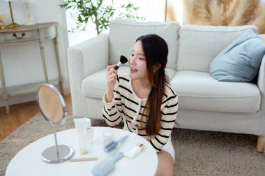 Genç Asyalı kadın evde makyaj yapıyor.