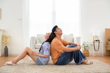 Parlak, havadar bir oturma odasında, yumuşak bir halının üzerinde sırt sırta verip rahatlayan bir çift..