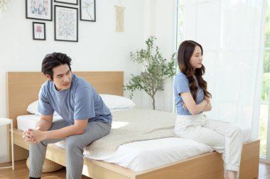 Bir çift, modern odalarında bir yatakta oturup, gerginlik ve üzüntü ifade ederler..