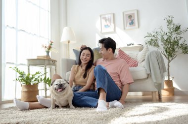 Köpekleri ile oynarlarken gülümseyen bir çift güzel ışıklandırılmış bir oturma odasında yumuşak bir halıda.