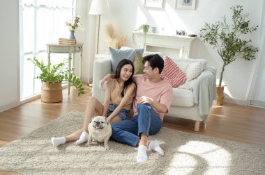 Köpekleri ile oynarlarken gülümseyen bir çift güzel ışıklandırılmış bir oturma odasında yumuşak bir halıda.