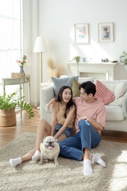 Köpekleri ile oynarlarken gülümseyen bir çift güzel ışıklandırılmış bir oturma odasında yumuşak bir halıda.