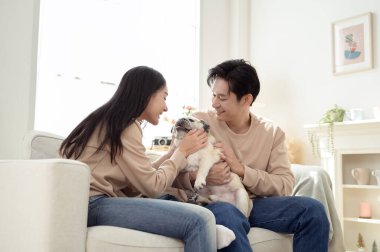 Köpekleri ile oynarlarken gülümseyen bir çift güzel ışıklandırılmış bir oturma odasında yumuşak bir halıda.