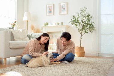 Köpekleri ile oynarlarken gülümseyen bir çift güzel ışıklandırılmış bir oturma odasında yumuşak bir halıda.