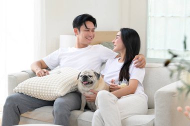 Neşeli bir çift kanepede birlikte oturur, güneşli bir yerde tatlı köpekleri ile atıştırmalıkları paylaşır..