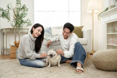 Sıcak, davetkar bir oturma odasında köpekleri ile oynarken birlikte gülen bir çift..