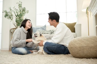 Sıcak, davetkar bir oturma odasında köpekleri ile oynarken birlikte gülen bir çift..