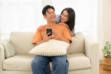 Bir çift, bir kanepede oturup, akıllı telefona bakarken neşe anlarını paylaşıyor..