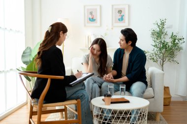 Bir çift, rahat, aydınlık bir ofis ortamında terapistle sohbet ediyor..