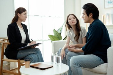 Bir çift, rahat, aydınlık bir ofis ortamında terapistle sohbet ediyor..