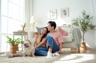 Köpekleri ile oynarlarken gülümseyen bir çift güzel ışıklandırılmış bir oturma odasında yumuşak bir halıda.