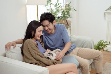 Köpekleri ile oynarlarken gülümseyen bir çift güzel ışıklandırılmış bir oturma odasında yumuşak bir halıda.