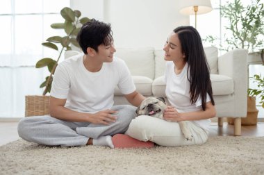 Köpekleri ile oynarlarken gülümseyen bir çift güzel ışıklandırılmış bir oturma odasında yumuşak bir halıda.