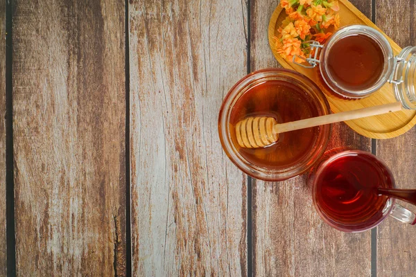 Sıcak bir organik bal, bitkisel çay ve kırsal bir masada ustalıkla hazırlanmış taze malzemeler.