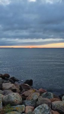 Sakin ve huzurlu bir günbatımı. Sakin suların üzerindeki gökyüzünü resmediyor. Kayalık kıyılarla mükemmel çerçevelenmiş.