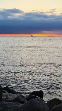 Engin okyanus üzerinde güzel ve sakin bir gün batımı manzarası, renkli gökyüzü ve kayalık bir kıyı şeridi.