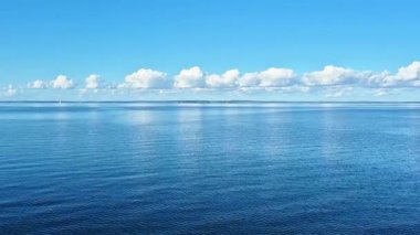 Sakin ve huzurlu bir okyanus manzarası ve zarif bir şekilde suya yansıyan güzel bulutlar.