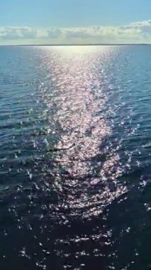 Huzurlu ve huzurlu bir ışıldayan su manzarası. Arkaplanda dağınık bulutlar olan güneş ışığını güzel yansıtan bir manzara.