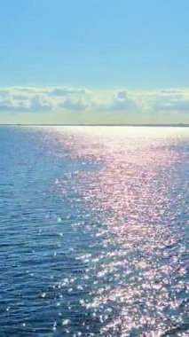 Işıldayan okyanus sularının büyüleyici ve büyüleyici görüntüsü parlak gökyüzünün altındaki güneş ışığını parlak bir şekilde yansıtıyor.