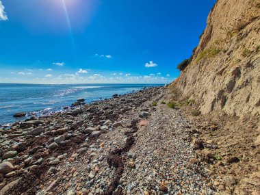 Göz kamaştırıcı ve güzel bir kıyı manzarası kayalık bir kıyıya, engin bir denize ve üzerinde parlak mavi gökyüzüne sahiptir.