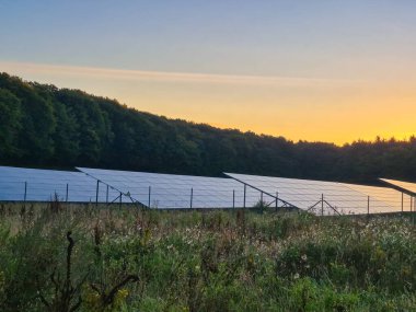 Bereketli bir ortamda, güzel bir altın gün batımının altına kurulmuş güneş panellerinin huzurlu ve huzurlu bir görüntüsü.