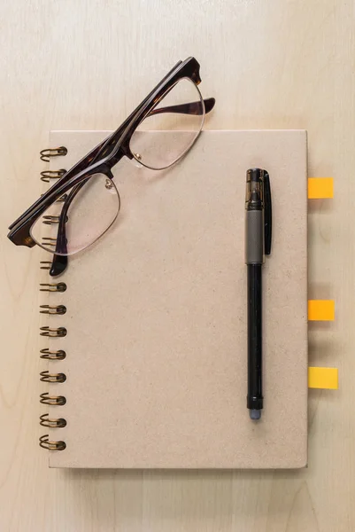 Braunes Notizbuch Mit Brille Und Schwarzem Stift Auf Holzhintergrund — Stockfoto