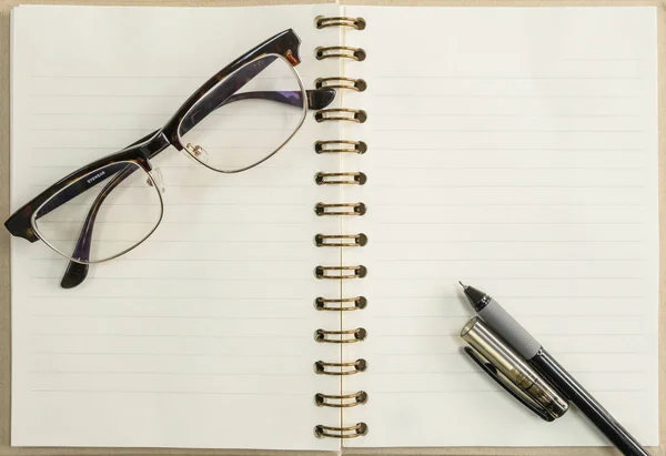 Bolígrafo negro y cuaderno con anteojos sobre fondo de madera debajo — Foto de Stock