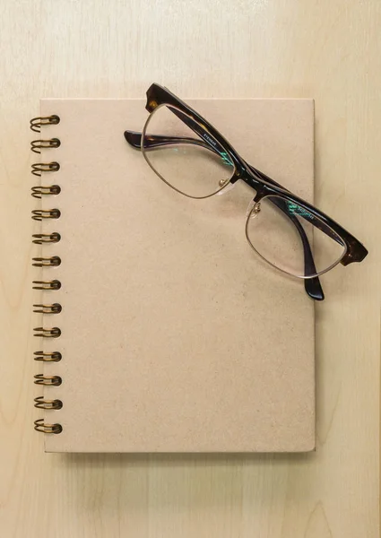 Braunes Notizbuch mit Brille auf Holzhintergrund unter Fenster l — Stockfoto