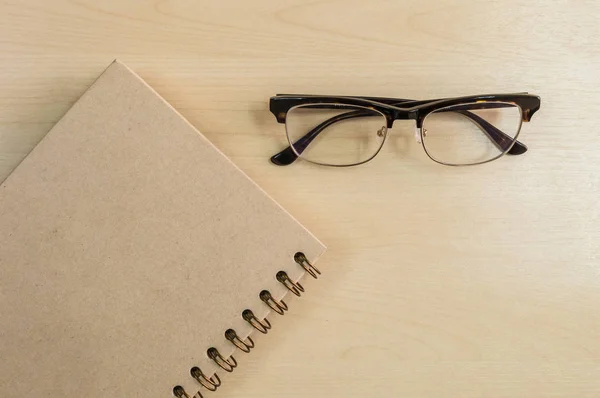Brun anteckningsbok med glasögon på trä bakgrund under fönster l — Stockfoto