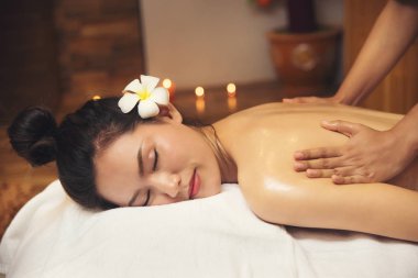 Güzel ve genç birbayan Spa Masaj salonu ve beyaz çiçek kulağı üzerinde elde.