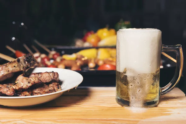 pouring beer with barbecue pork grill in background.