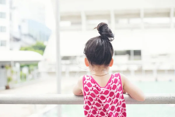 Děti nosí růžové šaty a dívají se na bazén — Stock fotografie