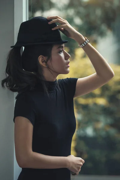 Портрет красивой азиатки в темном платье и черной шляпе с — стоковое фото