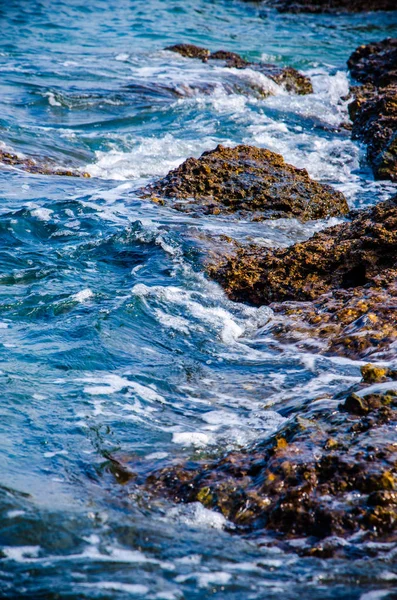 Les vagues se brisent sur les rochers du rivage. — Photo