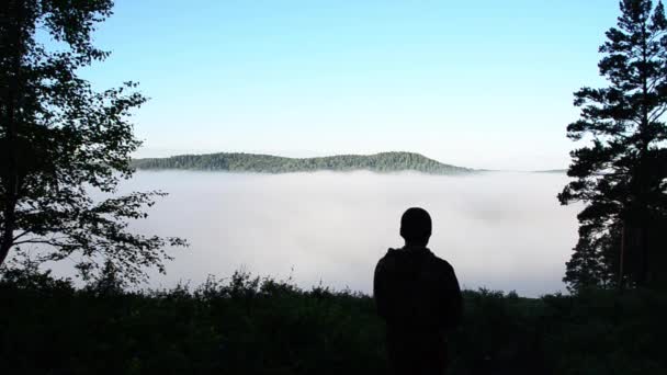 湖の上の朝の霧とシャワーの清潔感 男は手を開いて山の上に立っている ジェスチャーの自由 — ストック動画