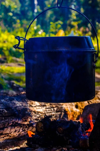 stock image fire burns in the campaign. pot of tea by the fire