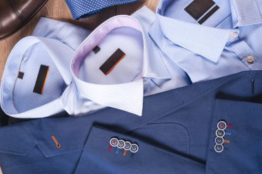 Klasik erkek kıyafetleri - mavi takım, gömlekler, kahverengi ayakkabılar, kemer ve kravat ahşap arka planda.