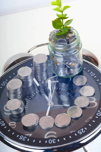 Monedas con planta y reloj, aisladas sobre fondo blanco. concepto de ahorro — Foto de Stock
