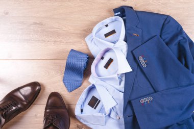 Klasik erkek kıyafetleri - mavi takım, gömlekler, kahverengi ayakkabılar, kemer ve kravat ahşap arka planda.