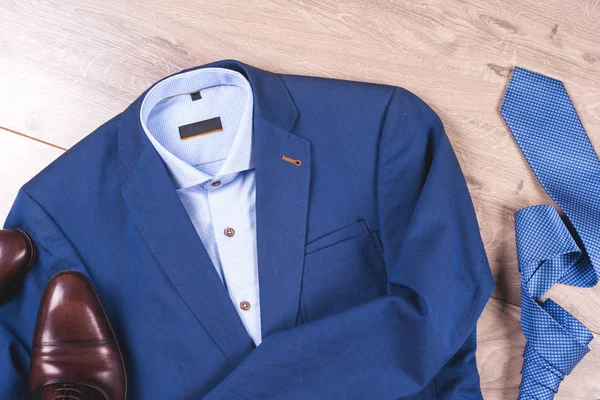 Conjunto de ropa clásica para hombre - traje azul, camisas, zapatos marrones, cinturón y corbata sobre fondo de madera. —  Fotos de Stock