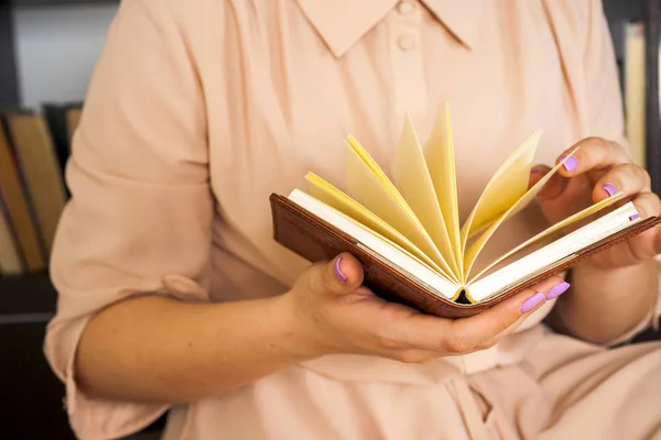 Fiatal lány könnyű ruhában könyvet olvas. A női kezek könyvet tartanak a kezükben. — Stock Fotó