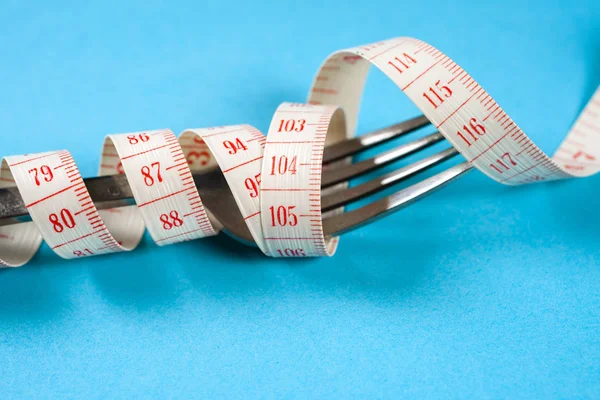 Tenedor con centímetro sobre fondo azul, dieta, estilo de vida saludable . — Foto de Stock