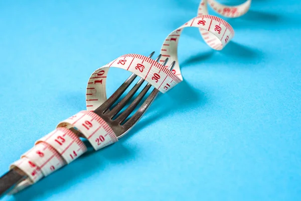 Tenedor con centímetro sobre fondo azul, dieta, estilo de vida saludable . — Foto de Stock