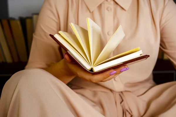 Hafif elbiseli genç kız bir kitap okuyor. Kadın elleri ellerinde bir kitap tutuyor. — Stok fotoğraf