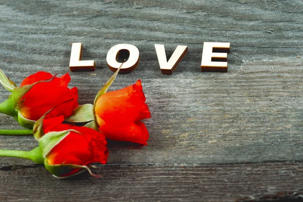 Quatro blocos de alfabeto rústico soletrando Amor com rosa vermelha em madeira — Fotografia de Stock