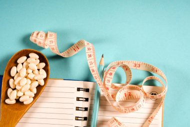 Bir yaprağına diyet planı ve tahta kaşıkla bir ölçüm bandı bir mavi arka plan, diyet, sağlıklı yaşam tarzı.