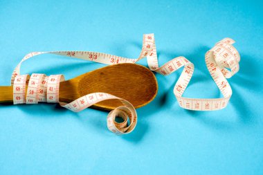Tahta kaşıkla bir ölçüm bandı bir mavi arka plan, diyet, sağlıklı yaşam tarzı.