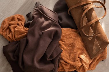 Yere dökülen dağınık sonbahar kıyafetleri yün ve pamuk sonbahar forması, süet çanta, hızlı moda konsepti..